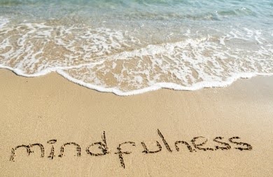 Picture of beach with mindfulness written on the sand