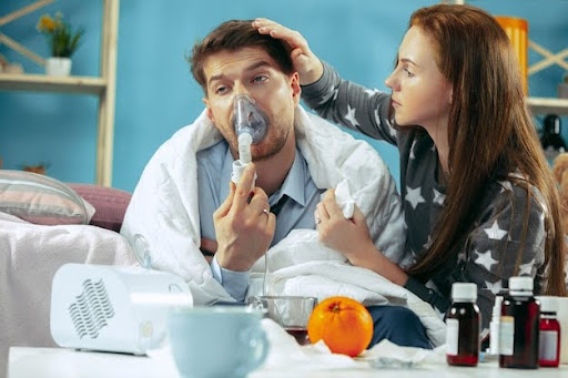 Young man using a nebulizer to relieve shortness of breath in asthma.
